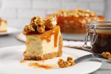 Piece of delicious caramel cheesecake with popcorn on table, closeup