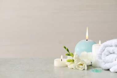 Güzel bir spa kompozisyonu, yanan mum, sarılmış havlu ve beyaz masa üzerinde çiçekler. Metin için boşluk