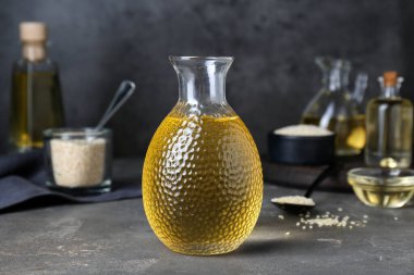 Gri masadaki cam şişede taze susam yağı.