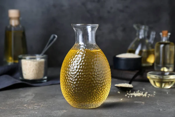Fresh sesame oil in glass bottle on grey table