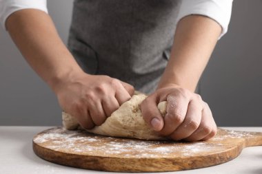 Gri duvarın yanındaki masada hamur yoğuran adam, yakın plan.