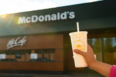 SAVAŞ, POLAND - 16 EYLÜL 2022: Dışarıdaki restoranın yakınında soğuk McDonald 's içeceği tutan kadın, yakın plan