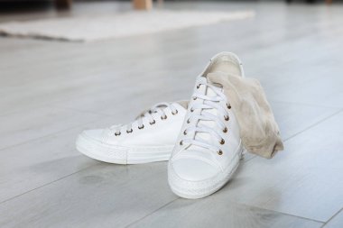 Beyaz ahşap zeminde kirli çorapları olan spor ayakkabıları.