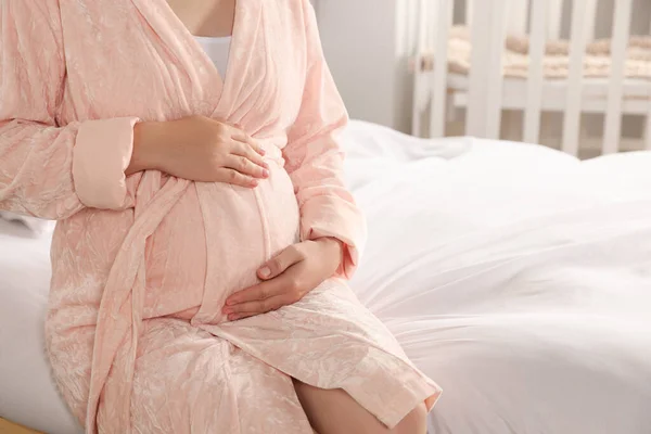 妊娠中の女性のバスローブの上のベッドで自宅で クローズアップ — ストック写真