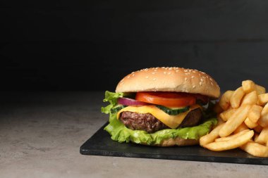 Gri masada servis edilen lezzetli hamburger ve patates kızartması. Metin için boşluk