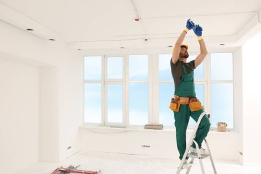 Elektrikçi kabloları kapalı alanda yalıtım bandıyla onarıyor.