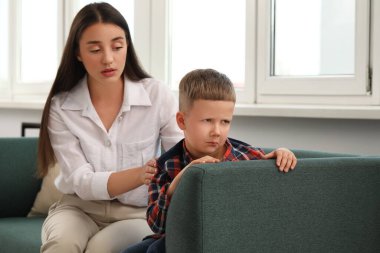Psychologist working with unhappy little boy in office. Mental health problems