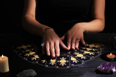 Soothsayer predicting future with tarot cards at table in darkness, closeup clipart