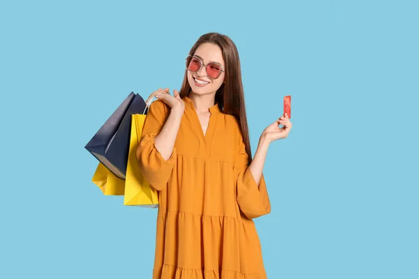 Glückliche Junge Frau Mit Einkaufstaschen Und Kreditkarte Auf Hellblauem Hintergrund — Stockfoto