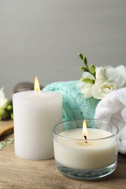 Yanan mumlar ve ahşap masa üzerinde farklı spa ürünleri olan güzel bir kompozisyon.