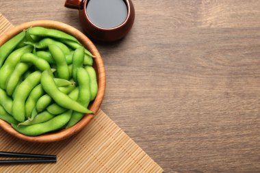 Ahşap masada soya sosuyla servis edilen kabuklu yeşil edamame fasulyeleri. Metin için boşluk