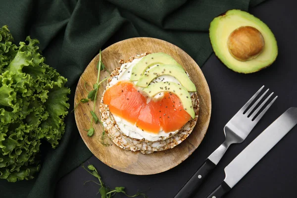 stock image Crunchy buckwheat cakes served with cream cheese, salmon and avocado on black table, flat lay