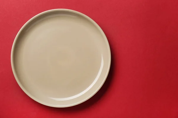 红色背景的空米色陶瓷盘 顶部视图 案文的篇幅 — 图库照片