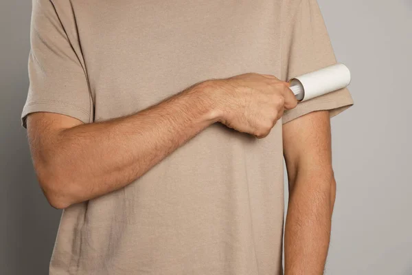 stock image Man using lint roller on light grey background, closeup