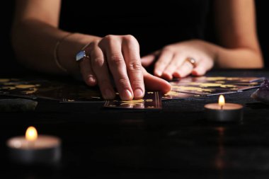 Kahin, karanlıkta tarot kartlarıyla geleceği tahmin ediyor. Yakın plan.