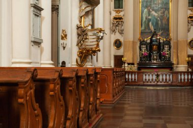 Kilise içi kutsal simgeler ve ahşap banklarla dolu.