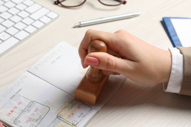 Ukrayna, Lviv - 6 Eylül 2022: Beyaz ahşap masada pasaport basan kadın, yakın plan