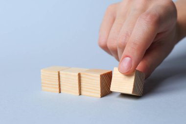 Işıklı arka planda küpleri düzenleyen kadın, yakın plan. Fikir kavramı