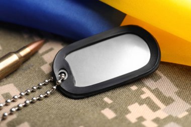 Piksel kamuflajında askeri kimlik kartı, kurşun ve Ukrayna bayrağı, yakın plan.