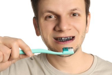 Man brushing teeth with charcoal toothpaste on white background, closeup