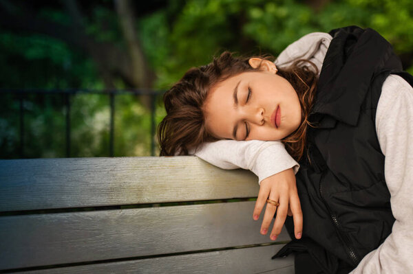 Tired woman sleeping on wooden bench outdoors