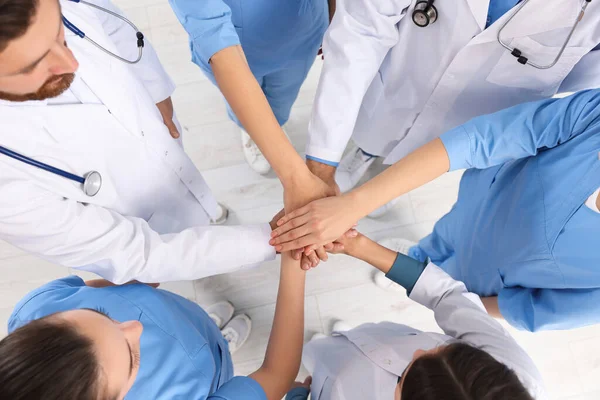 stock image Team of medical doctors putting hands together indoors, above view