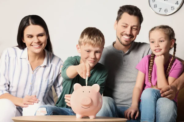 Szczęśliwa Rodzina Wkłada Pieniądze Skarbonki Przy Stole Pokoju — Zdjęcie stockowe