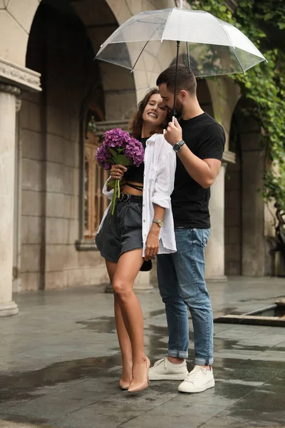 Stock image Young couple with umbrella enjoying time together under rain on city street