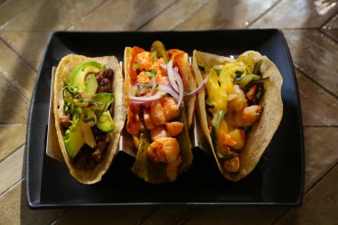 Masanın üstünde karides ve sebzeli lezzetli tacolar var.