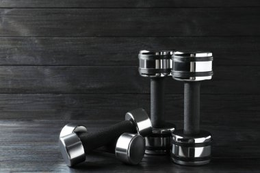 Set of metal dumbbells on black wooden table