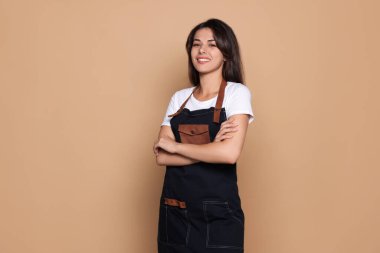 Soluk turuncu arka planda önlüklü mutlu profesyonel kuaför.