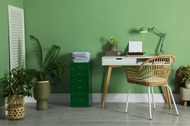 Writer's workplace with typewriter on wooden desk near pale green wall in room