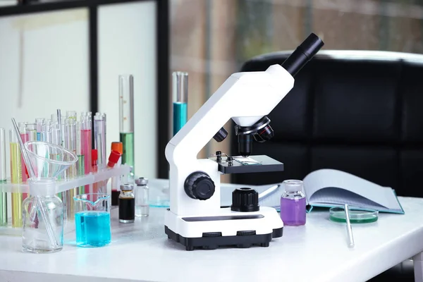 Modern microscope with glass slide on white table in laboratory