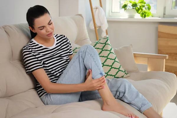 Junge Frau Reibt Sich Wundes Bein Auf Sofa Hause — Stockfoto
