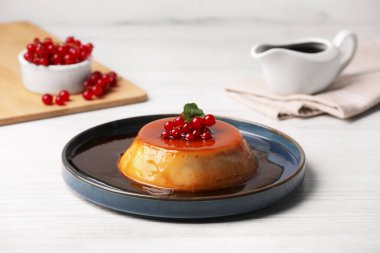 Kırmızı üzümlü karamelli puding ve beyaz ahşap masada nane.