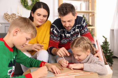 Aileleri evde güzel Noel tebrik kartları hazırlayan sevimli çocuklar.