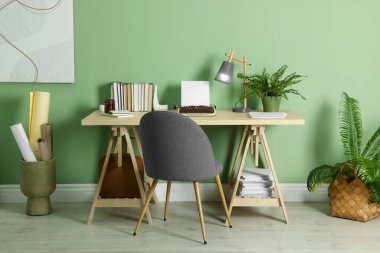 Writer's workplace with typewriter on wooden desk near pale green wall in room