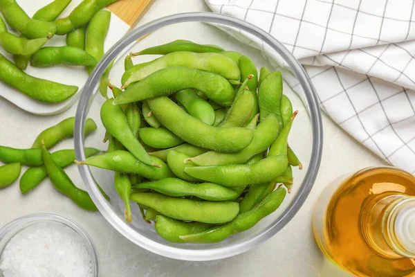 Green edamame beans in pods served on light grey table, flat lay