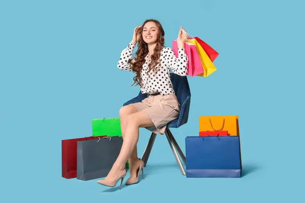 Ευτυχισμένη Γυναίκα Κρατώντας Πολύχρωμες Τσάντες Ψώνια Στην Πολυθρόνα Κατά Γαλάζιο — Φωτογραφία Αρχείου