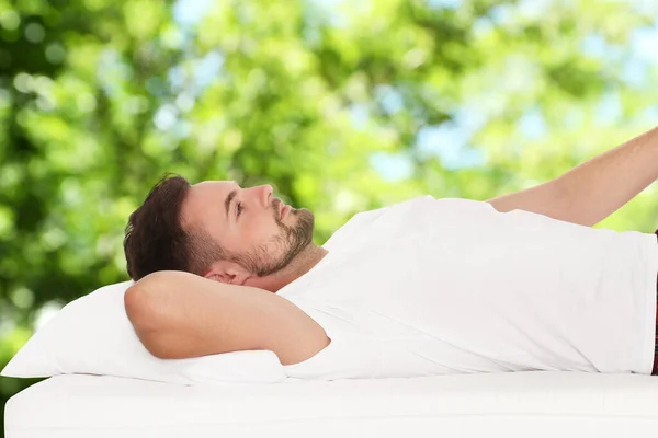 Man Lying Comfortable Mattress Blurred Green Background Bokeh Effect Sleep — Stock Photo, Image