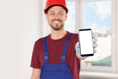 Üniformalı profesyonel bir tamirci. Kapalı alanda telefonu var. Eline odaklan.
