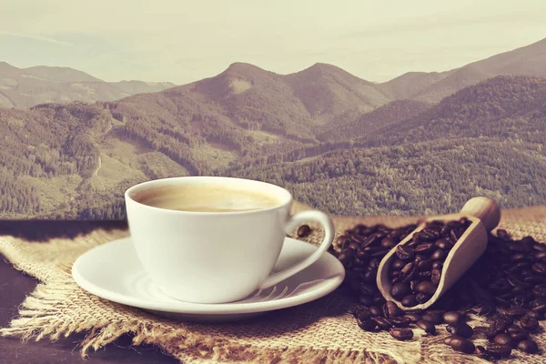 stock image Cup of aromatic hot coffee on wooden table and beautiful view of mountain landscape