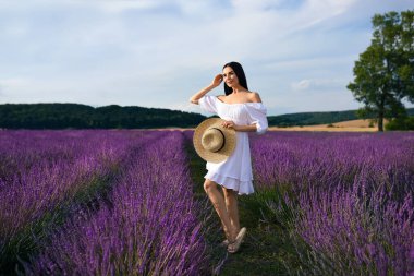 Beautiful young woman walking in lavender field