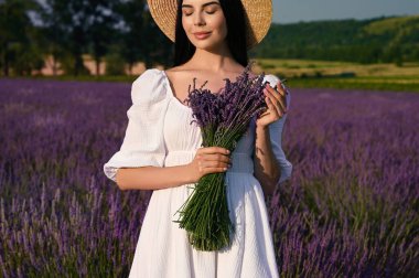 Beautiful young woman with bouquet in lavender field