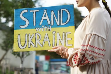 Ulusal bayrak renginde posterler taşıyan genç bir kadın Ukrayna 'nın önünde dikilsin, yakın plan