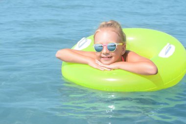Güneşli bir günde denizde şişme yüzüğü olan mutlu küçük kız.