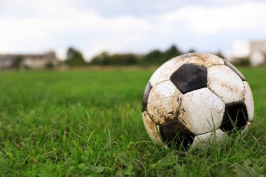 Açık havada yeşil çimlerde kirli futbol topu, metin için alan