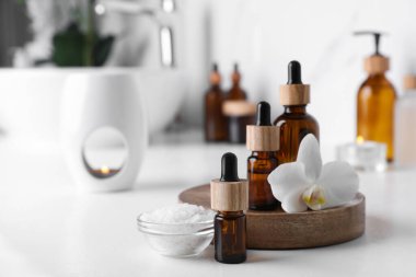 Temel yağlar, orkide çiçeği ve banyodaki beyaz tezgahın üzerinde deniz tuzu. Metin için boşluk