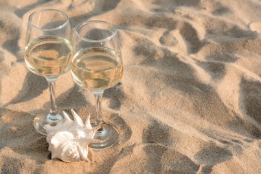 Bardaklar dolusu lezzetli şarap ve kumdaki deniz kabuğu, metin için yer.