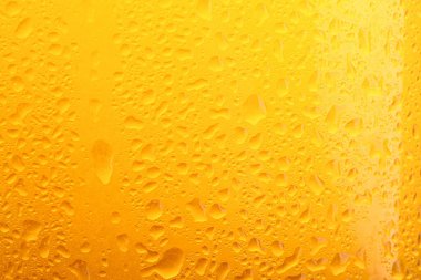 Glass of tasty cold beer with condensation drops as background, closeup